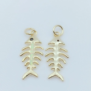 Gold-plated fish bone pendants with colorful opal inlay and black stone eyes on blue background