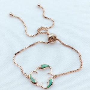 Detail of rose gold dolphin bracelet showing green opal inlays and sliding bolo clasp