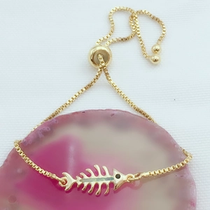 Detalle de pulsera ajustable de espina de pescado dorada con ópalo verde incrustado