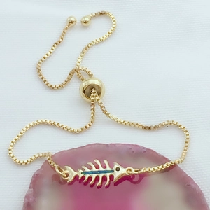 Vista detallada de pulsera de espina de pescado dorada con ópalo azul sobre ágata rosa