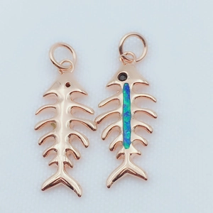Detailed macro view of two rose gold fish bone pendants with turquoise inlay and ring loop