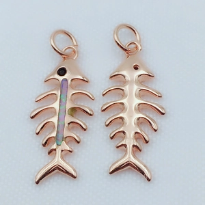 Detailed view of rose gold fishbone pendants with iridescent opal inlay on white surface