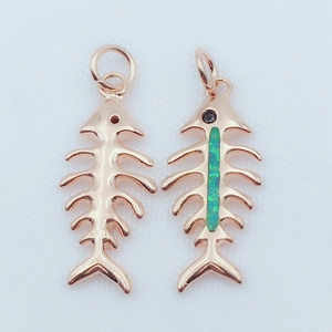 Macro shot of gold plated fishbone pendants with green opal stone and smooth metal finish