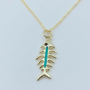 Detailed view of a gold-plated fishbone pendant with blue opal inlay on a fine chain