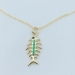 Close-up of gold plated fishbone pendant with iridescent green opal inlay and delicate chain