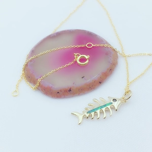 Detail of fishbone pendant necklace in gold-plated copper with green opal inlay