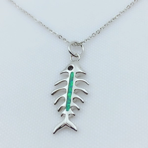 Macro view of silver-plated fish bone pendant with green opal inlay and delicate chain