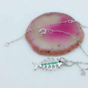 Detailed macro view of silver fishbone pendant with blue opal inlay on pink agate