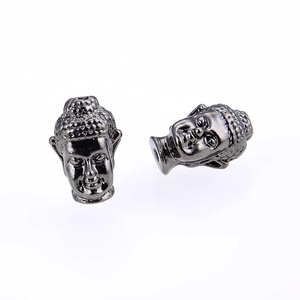 Nahaufnahme von zwei gun-schwarzen Buddha-Kopf-Perlen aus Metall mit Löchern für DIY-Schmuck