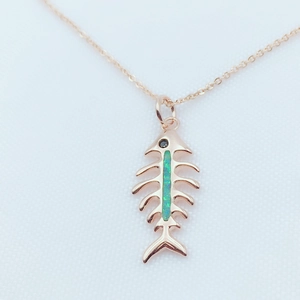 Close-up of rose gold fishbone pendant with green opal inlay and black diamond eye