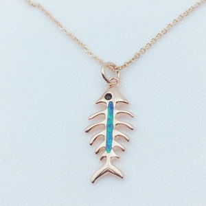 Detail shot of rose gold fishbone pendant with blue opal inlay and black gemstone eye