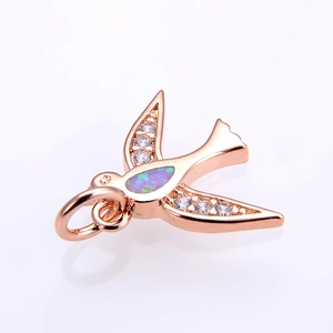 Detalle de un colgante de golondrina en oro rosa con alas de circón blanco y piedra ópalo