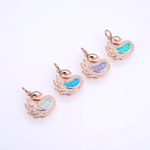 Rose gold swan pendant with opal inlay and zircon accents on white glossy surface