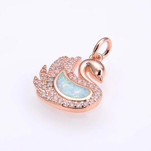 Macro view of swan pendant in rose gold with white crystals and iridescent opal inlay