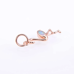 Macro shot of rose gold flamingo pendant featuring colorful opal inlay and polished metal