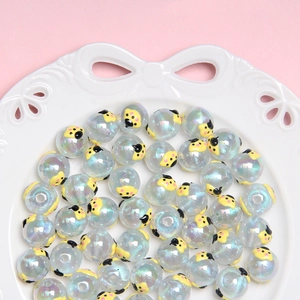 Macro shot of iridescent Christmas beads with ladybug patterns in a white ceramic dish