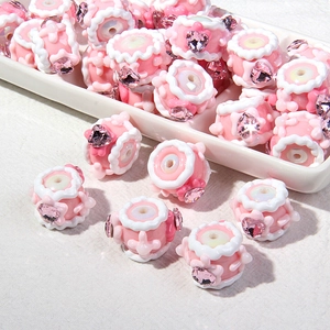 Makro-Detail von rosa Harzperlen mit Herzkristallen und weißem Wellenrand für DIY