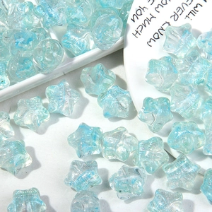 Cuentas de estrella azul claro translúcidas con purpurina en plato decorativo blanco