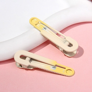 Detail of cream white and pale yellow hair clips with spring-loaded duckbill design