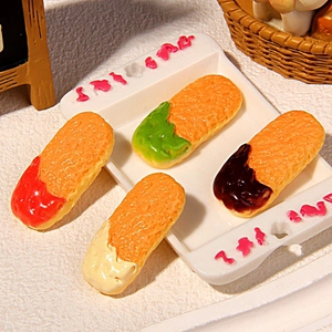 Miniature fake finger biscuits set with assorted cream toppings on a white serving tray
