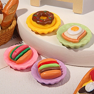 Detailed macro shot of miniature resin food models including donuts and burgers on colorful plates