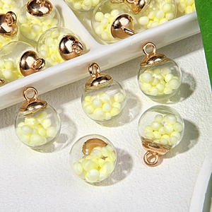 Detailansicht der Glaskugel-Anhänger mit Goldkappen und gelben Perlen für DIY-Schmuck