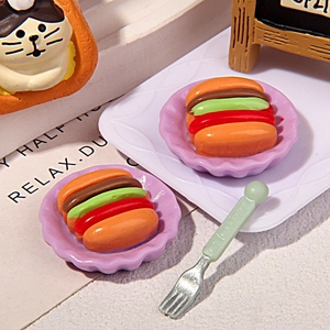 Miniature hot dog food models on purple plates with a tiny fork and cat decor