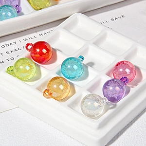 Macro detail of 15mm colorful bubble resin beads with hanging loops in white grid tray
