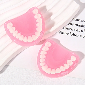 Macro shot of realistic resin teeth charms with pink translucent base for DIY keychain crafting
