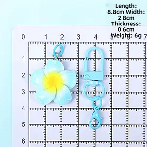 Detail view showing 8.8cm length of a blue resin plumeria flower keychain with carbine hook