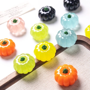 Vue détaillée de breloques citrouilles en résine colorée pour bricolage sur plateau