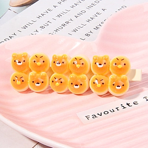Macro view of cute orange resin hair clip with cartoon bears and chicks on pink tray