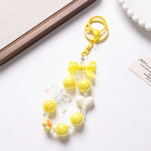 Detailed view of yellow beaded charm with bow and heart accents for phone or keys