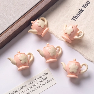 Detailed close-up of pink resin miniature teapots with cream flower patterns for dollhouses