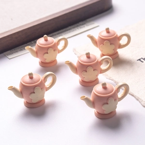 Macro detail of five mini pink resin teapots with cream lids for dollhouse DIY projects