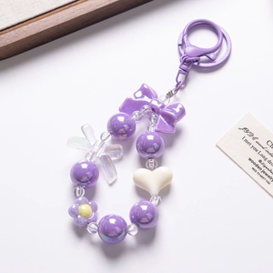 Macro view of purple beaded phone charm with resin bow and heart-shaped beads