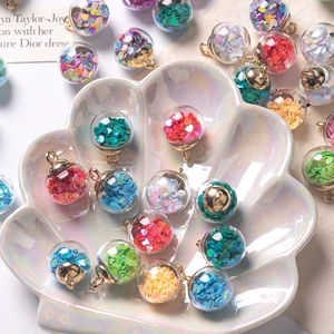 Macro shot of glass ball pendants with heart sequins in a shell tray for DIY jewelry