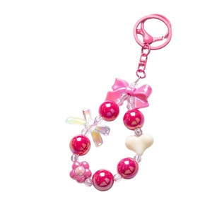 Pink Y2K beaded phone charm with bow and heart pendants on white background