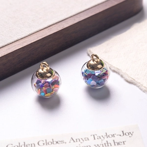 Macro detail of glass globe charms with colorful heart sequins and golden metal caps