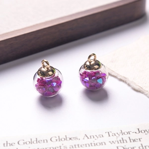 Macro shot of glass ball pendants with purple heart sequins and golden metal ring caps