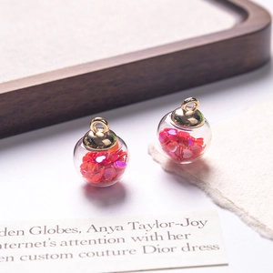 Detailed view of clear glass ball charms filled with pink heart sequins for DIY jewelry