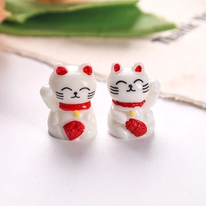 Macro detail of two miniature resin fortune cats with red ears and Lucky charms