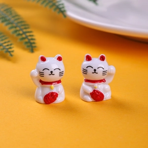 Detailed close-up of two miniature white resin Maneki Neko cats with red Fu character