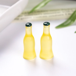 Close-up of miniature resin soda bottles with yellow bodies and green caps for dollhouse DIY