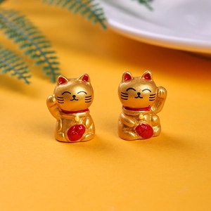 Close-up of golden resin lucky cat miniatures with intricate red and black details