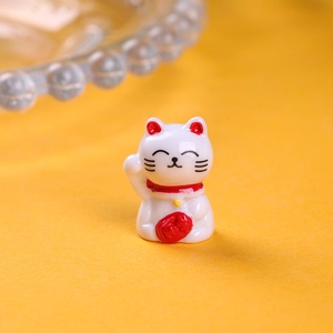 Close-up of white resin lucky cat figurine with red money bag and golden bell detail