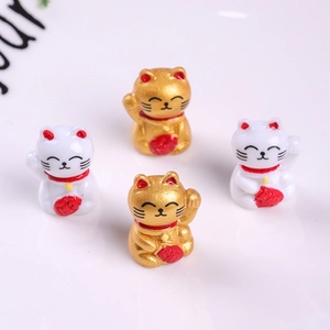 Detailed view of four mini lucky cat resin figurines in white and gold with red bags