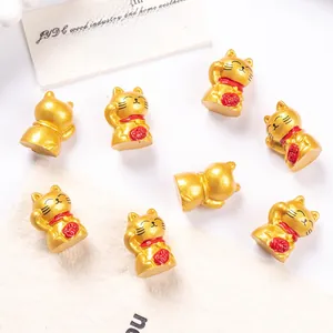 Detailed close-up of golden resin Maneki-neko miniatures with red collars and fortune bags