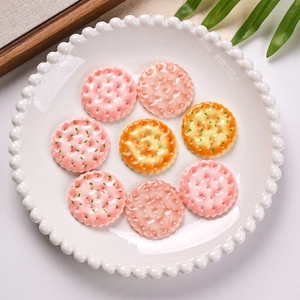Resin miniature cookies for DIY crafts on a white dotted plate with green leaves