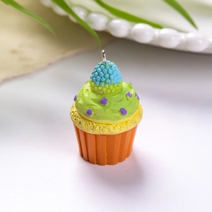 Κοντινό πλάνο μενταγιόν cupcake από ρητίνη με διακοσμητική κρέμα και πορτοκαλί βάση